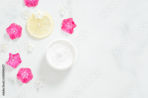 Top view of cosmetic lotion with pink flower petals and citrus lemon. Flatlay skin care beauty treatment with jar of body moisturizer. Organic cosmetic products  natural moisturizing cream concept.