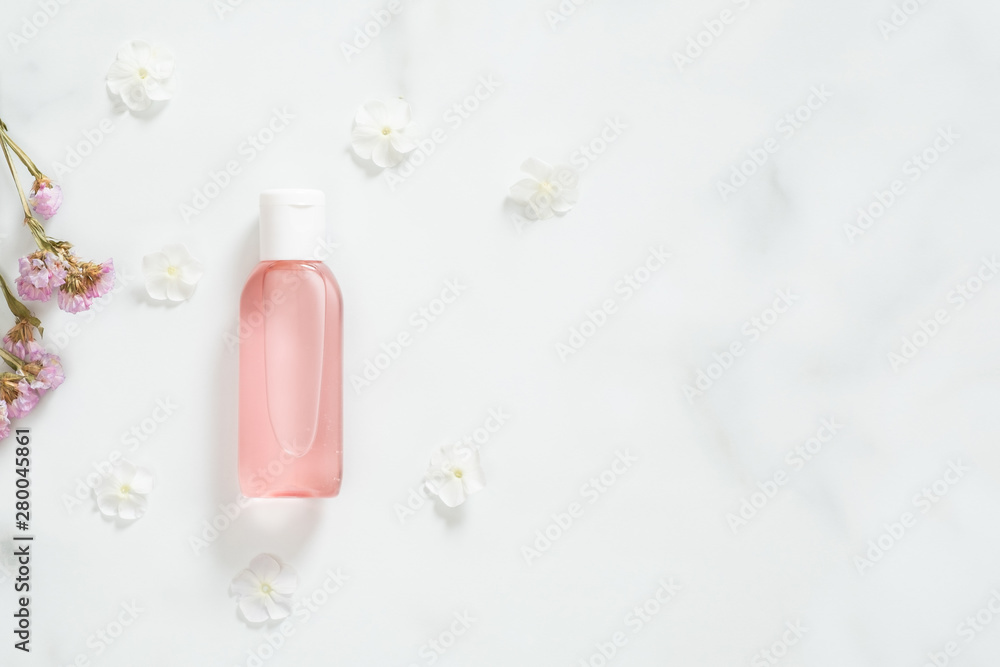 Cosmetic package containers with pink liquid lotion and flower petals on marble background. Minimal flat lay style composition, top view, overhead. Bio organic product, beauty and spa concept. Cosmetic package containers with pink liquid lotion and flower petals on marble background. Minimal flat lay style composition, top view, overhead. Bio organic product, beauty and spa concept.