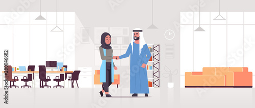arabic businesspeople man woman handshaking arab business partners couple hand shake during meeting agreement partnership concept modern co-working center office interior full length horizontal