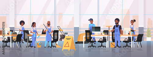 cleaners team in uniform working together cleaning service concept african american janitors using professional equipment modern co-working open space office interior flat full length horizontal