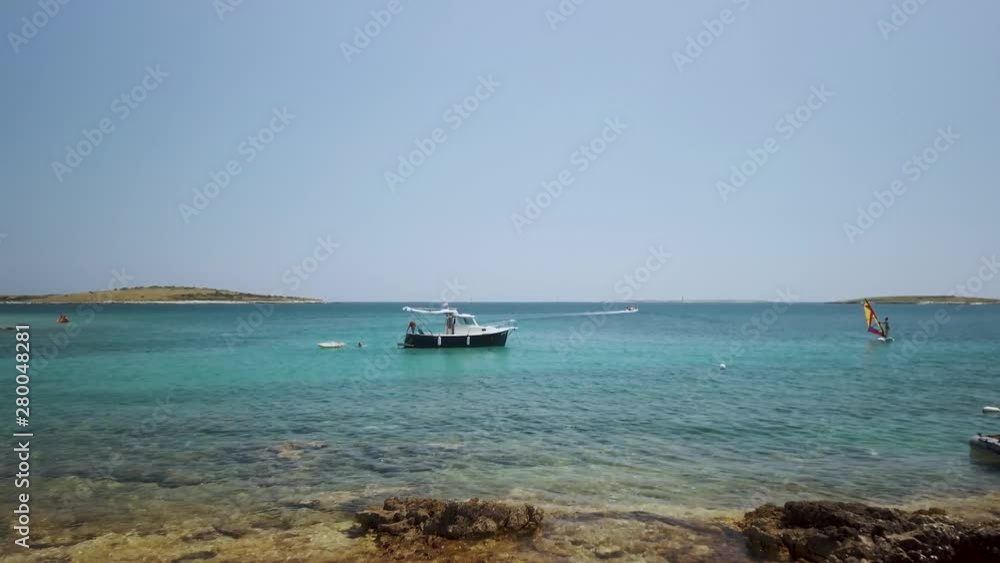 Clear costal waters on a rocky shore, boat and windsurfer AERIAL SHOT Clear costal waters on a rocky shore, boat and windsurfer AERIAL SHOT