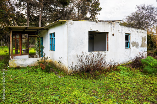 Exterior of an abandoned old white concrete house in the forest. © Cagkan