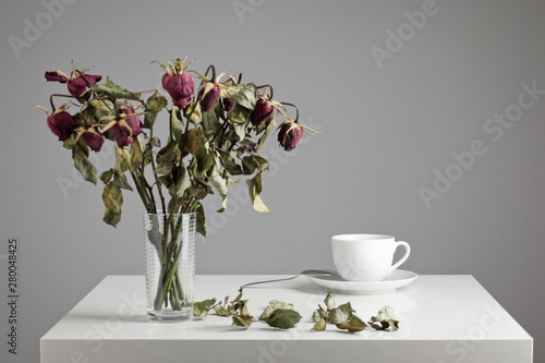 Cup of coffee with dried, dead flowers on a table photo