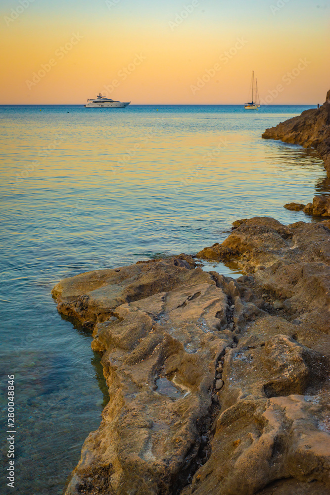 Luxury Boats in a Tranquil Bay in the Mediterranean Sea from the Shore of the Balearic Island of Mallorca at Sunset