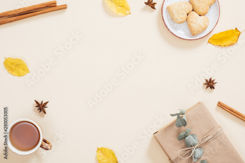 Pattern made of dry autumn leaves, gift box, cookies, cup of tea, cinnamon sticks. Fall flat lay. Top view. Autumn minimal concept