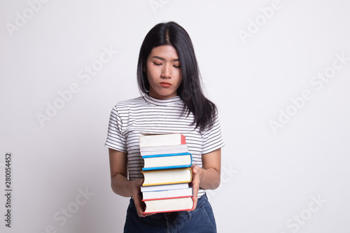 Unhappy young Asian woman studying with may books.