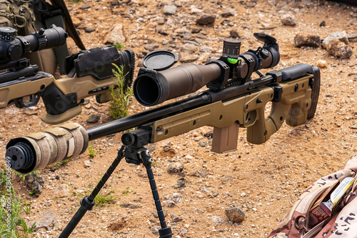 Suppressed Precision bolt-action rifle sitting on ground at outdoor range