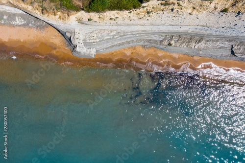 Aerial view of beautiflul rocky cliff and sandy beach by the ocean.