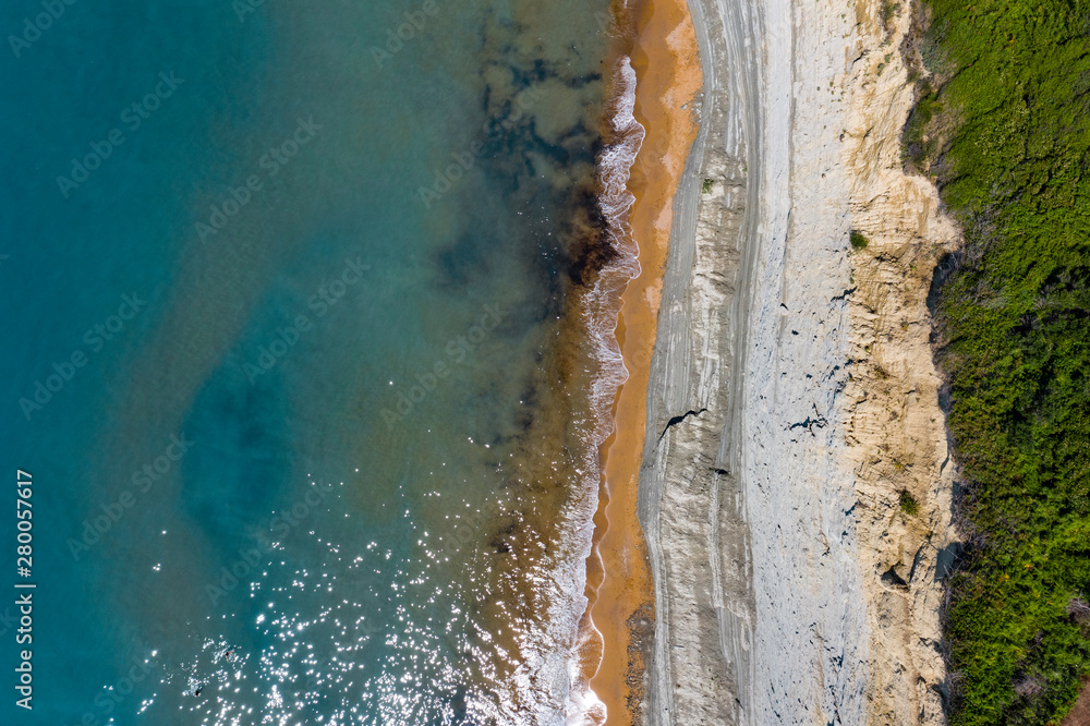 Aerial view of beautiflul rocky cliff and sandy beach by the ocean.