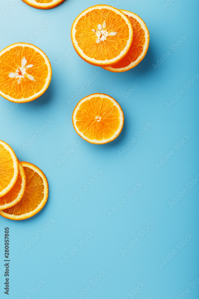 Round slices of juicy orange on a blue background, top view as a background substrate. Food background Round slices of juicy orange on a blue background, top view as a background substrate. Food background