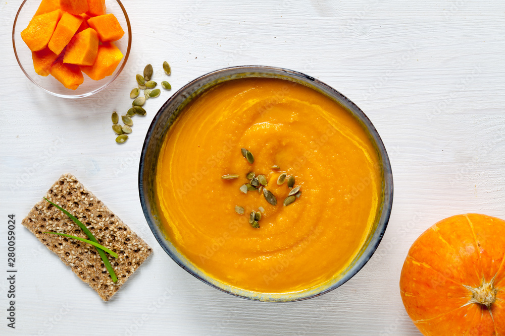 Pumpkin soup with pumpkin seeds on white wood background, top view Pumpkin soup with pumpkin seeds on white wood background, top view