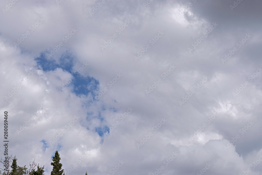 summer clouds gather over the forest near Fairbanks in Alaska showing an opening of blue sky over the tops of the trees summer clouds gather over the forest near Fairbanks in Alaska showing an opening of blue sky over the tops of the trees