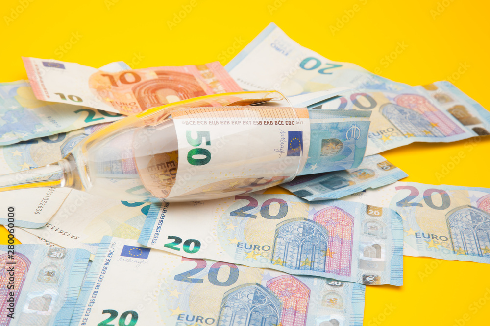 Obraz premium Copa de champagne, llena de billetes de dinero de curso legal. Copa de cristal llena de dinero y dinero encima de una superficie.