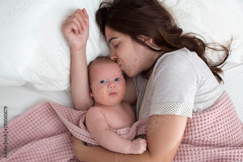 A brunette woman kisses a baby. Mom with baby closeup