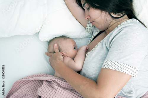 Brunette woman breastfeeds a baby. Mom with baby closeup
