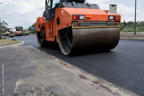 Close up of vibratory asphalt roller compactor on site, compacting new asphalt pavement in urban modern city