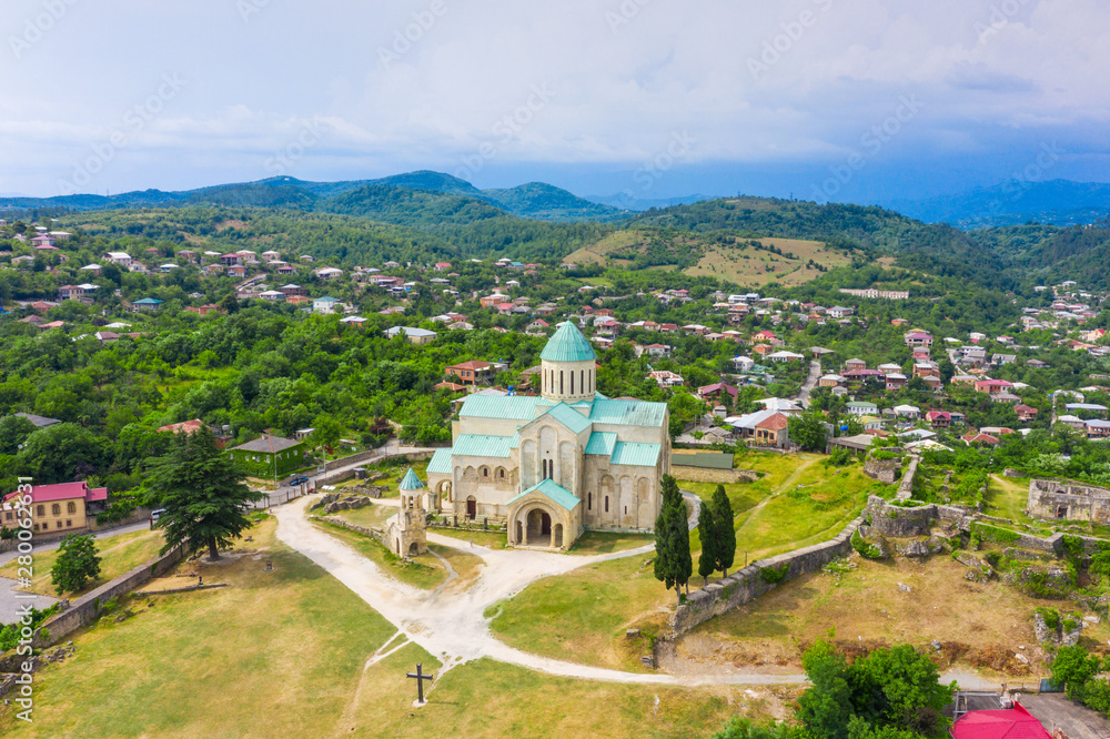 Panoramic summer view of the city of Kutaisi, Georgia. Bagrati's Cathedral and River Rioni and old houses with Red roofs. Mountains in the distance.