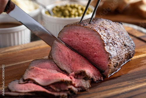 slicing eye of round roasted beef with knife photo