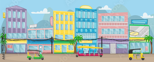 Asian street with colorful buildings, electric wires and tuk tuks on the roads.