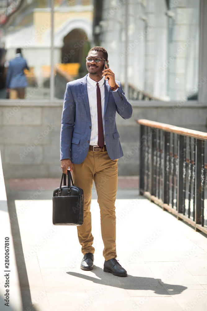 handsome young adult african man in suit and glasses talking on the phone handsome young adult african man in suit and glasses talking on the phone