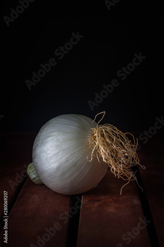 WHITE ONION ON WOODEN TABLE AND DARK BACKGROUND