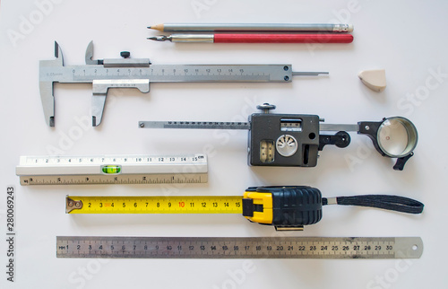Measuring instruments and tools insulated on a white sheet. Set with various rulers, planimeter, caliper, pencil, ink pen for use in manufacturing process industrial sector.