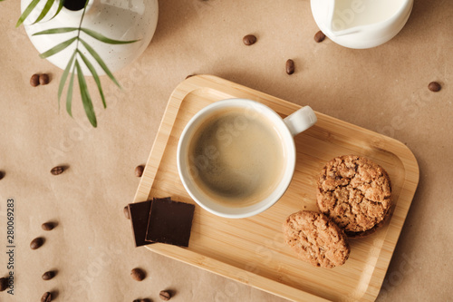coffee with milk and oatmeal cookies and chocolate on a wooden tray