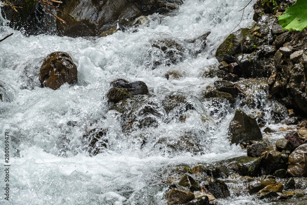 A powerful mountain stream flows down from the rocks and stones. A powerful mountain stream flows down from the rocks and stones.