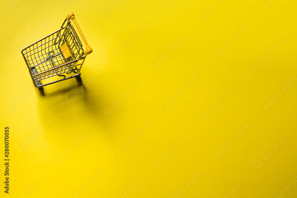 Small trolley in a yellow background. Shopping online concept Small trolley in a yellow background. Shopping online concept
