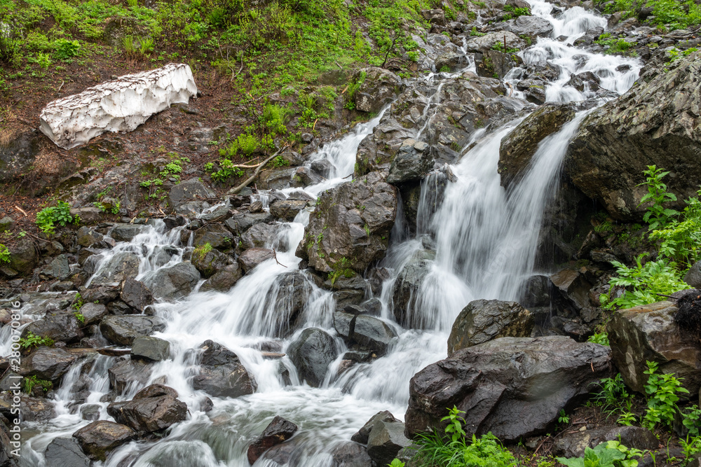A powerful mountain stream flows down from the rocks in a dense fog. A powerful mountain stream flows down from the rocks in a dense fog.