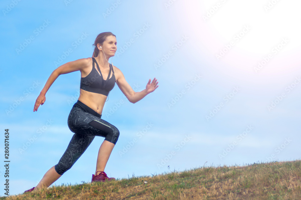 Side view beautiful woman running on the edge of the hill. background blue sky