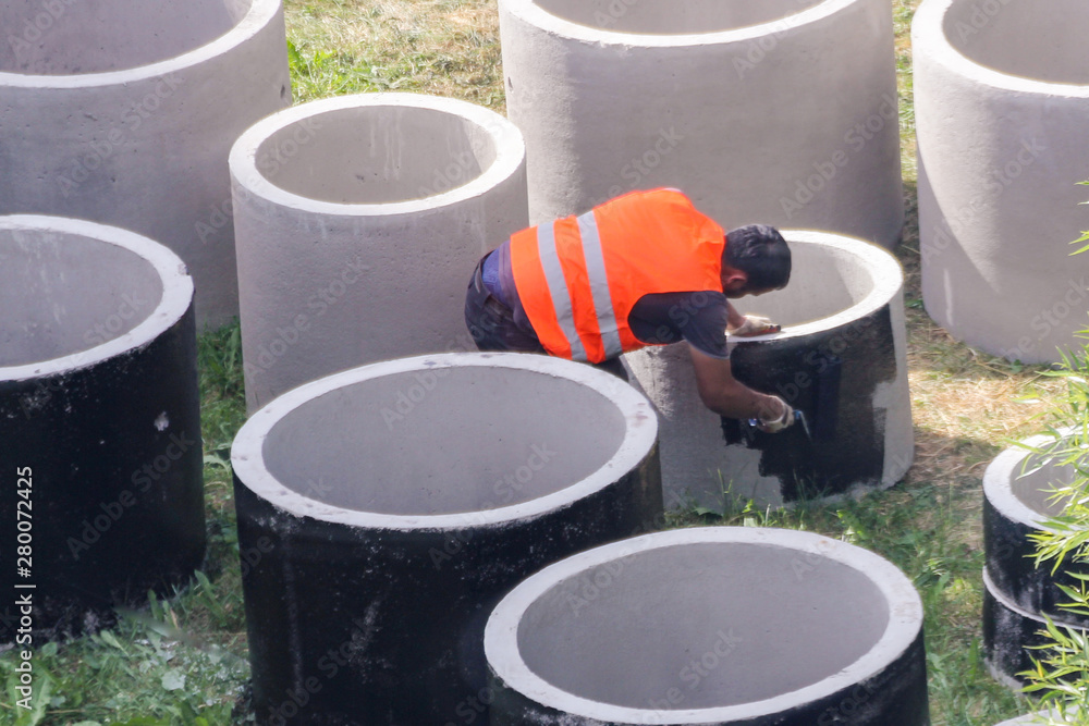 Worker paints concrete rings.