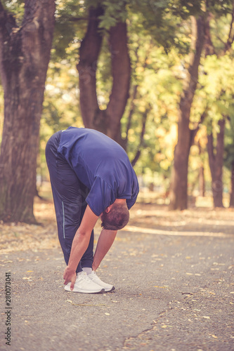 Young sporty man doing stretching exercise in the park