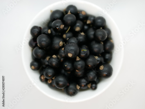 Ripe black currant berries in a small white Cup on a white background. Black currant harvest. Natural vitamin. Healthy food. vegetarian food.
