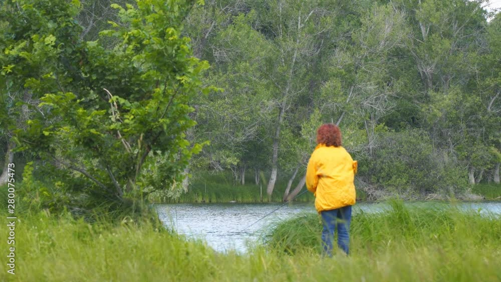Woman in yellow jacket fishing spinning on the lake