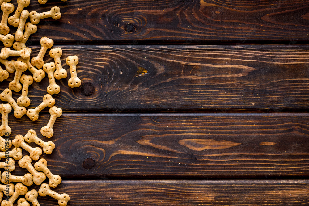 Dry pet food in shape of bone on wooden background top view copyspace Dry pet food in shape of bone on wooden background top view copyspace