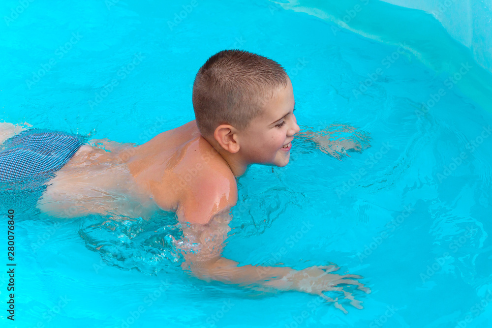 little cute boy swimming in the pool with turquoise water in the summer holidays little cute boy swimming in the pool with turquoise water in the summer holidays