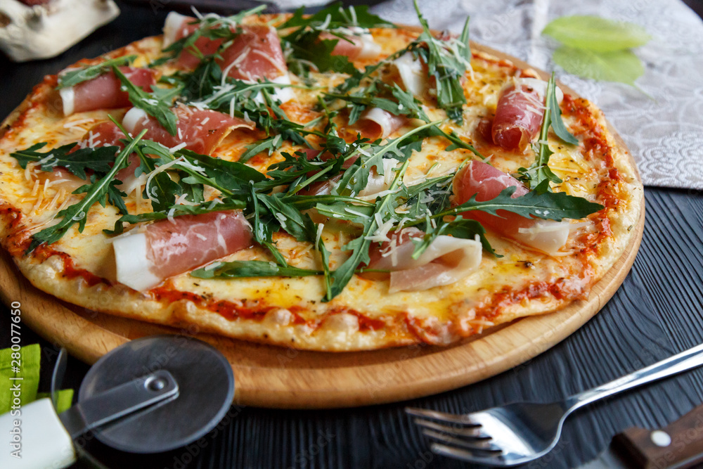 Pizza with bacon, cheese and herbs on a black wooden background Pizza with bacon, cheese and herbs on a black wooden background