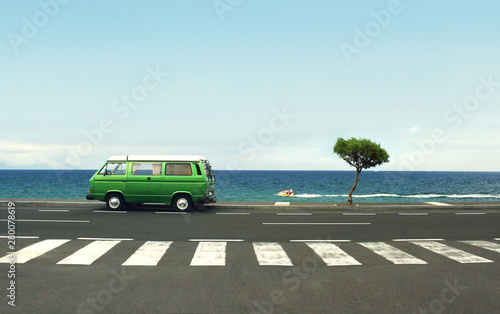 Photo of a green van on the road and sea