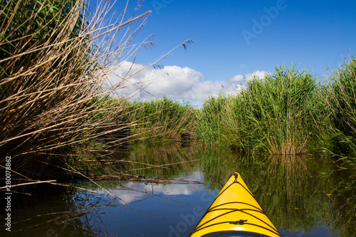 Paddle through a narrow canal surrounded by reeds.