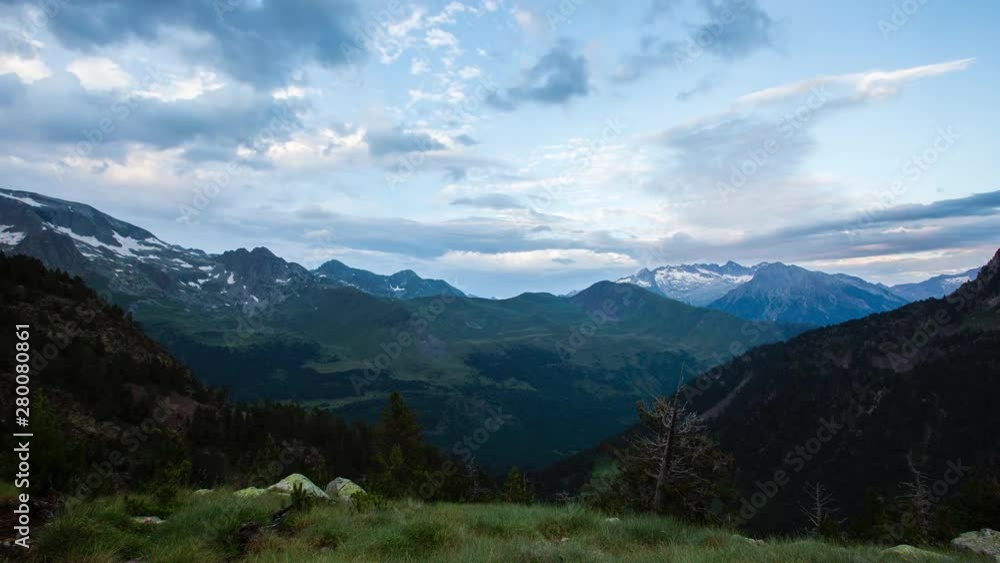 Dramatic pink and blue clouds drifting across evening sky above rugged mountain peaks in Pyrenees mountains of Spain, revealing stunning alpine landscape Dramatic pink and blue clouds drifting across evening sky above rugged mountain peaks in Pyrenees mountains of Spain, revealing stunning alpine landscape