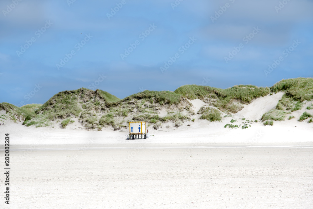Toilettenhäuschen am weißen Strand mit Dünen auf einer Insel