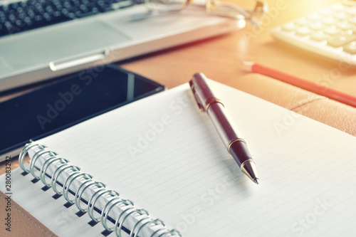 Notebook with calculator, keyboard and pen on table