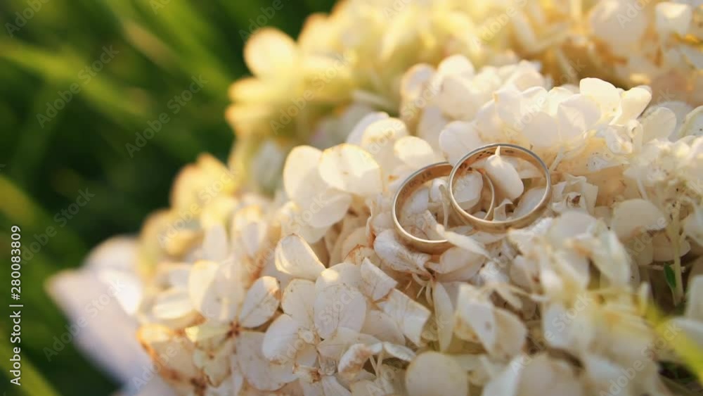 Golden wedding lock rings on a bouquet of flowers, close up Golden wedding lock rings on a bouquet of flowers, close up