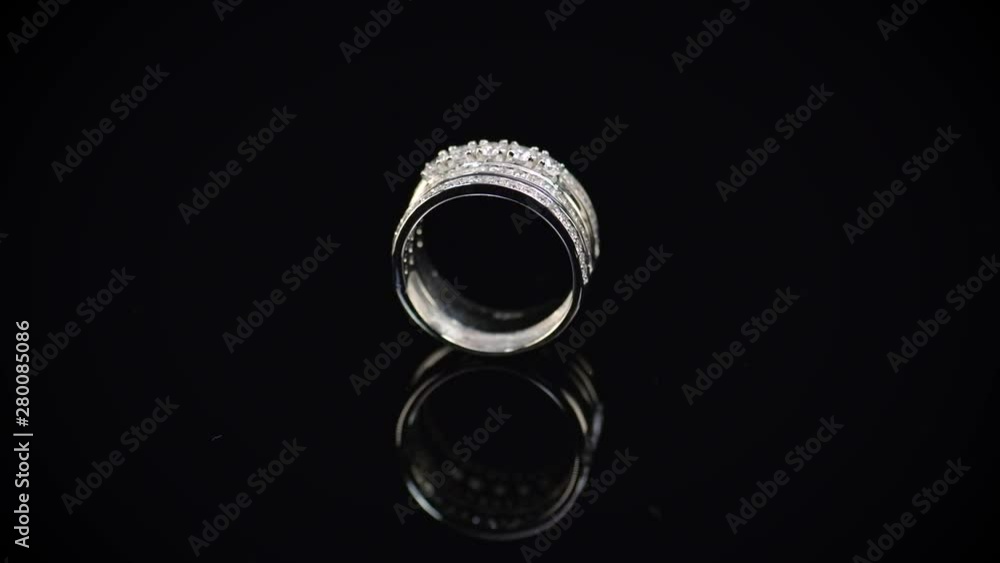 Beautiful diamond ring made of white gold or platinum. Wedding ring rotating on black background Beautiful diamond ring made of white gold or platinum. Wedding ring rotating on black background