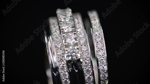 Wedding diamond ring slowly rotating on black background. Luxury jewelry made of silver or platinum