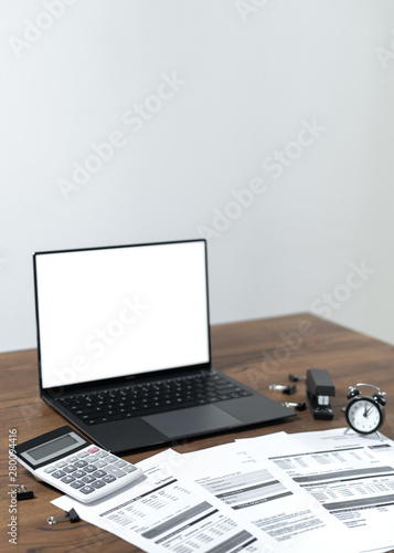 Modern laptop and documents on wooden table