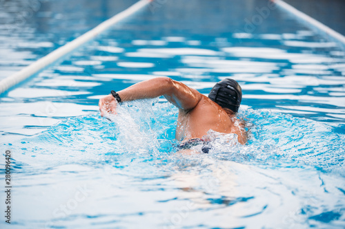 Athletic Young man swimming the back crawl in a pool. Swimming competition.