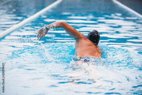 Athletic Young man swimming the back crawl in a pool. Swimming competition.