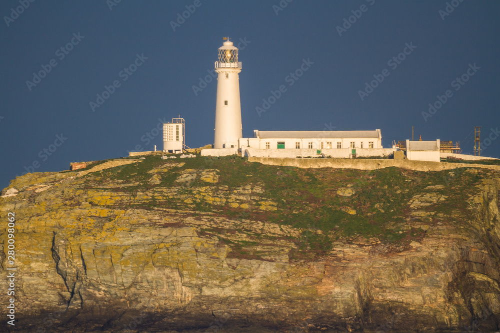 Lighthouse on rocky outcrop in morning light, landscape Lighthouse on rocky outcrop in morning light, landscape